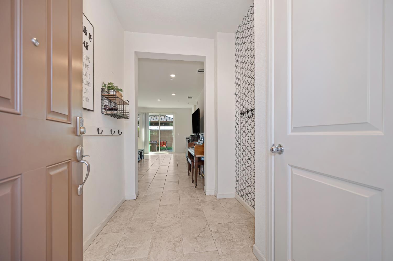 Entry hallway with tile flooring and patterned accent wall, looking toward the living area.