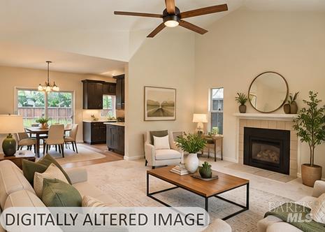 Living room with a fireplace, round mirror, ceiling fan, and adjoining dining area and kitchen.