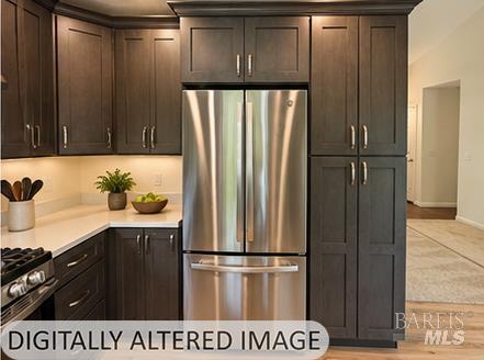 Kitchen with dark wood cabinets, stainless steel refrigerator, and gas range.