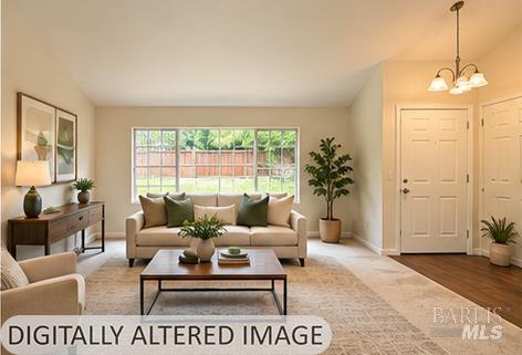 Staged living room with a beige sofa, large window overlooking a fenced yard, and coffee table.