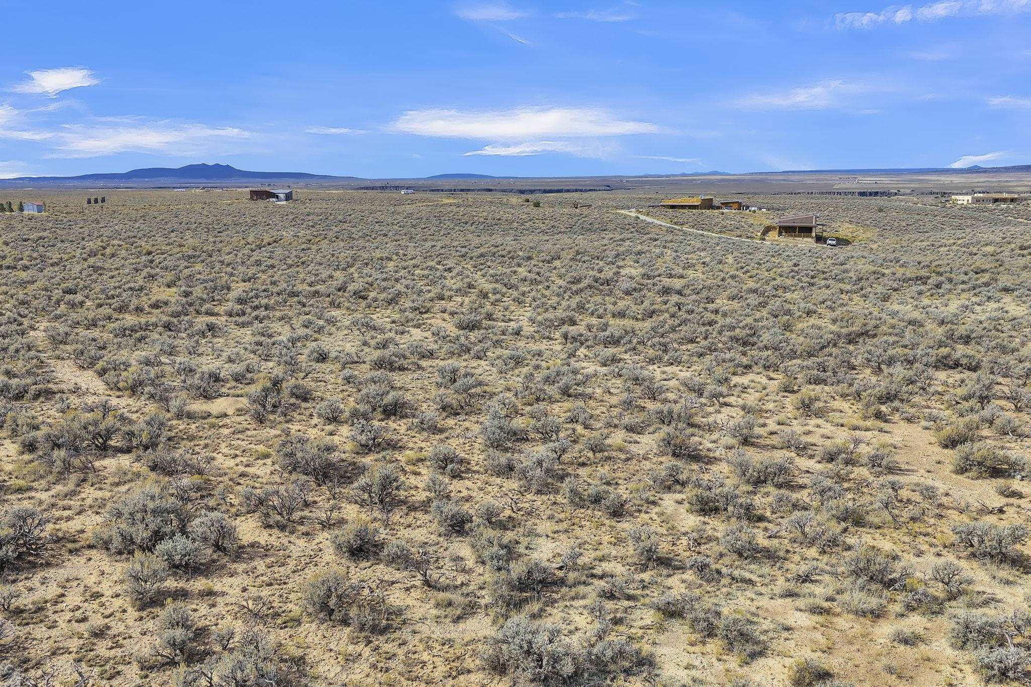 Open scrubland acreage with distant buildings and a mountain range on the horizon.