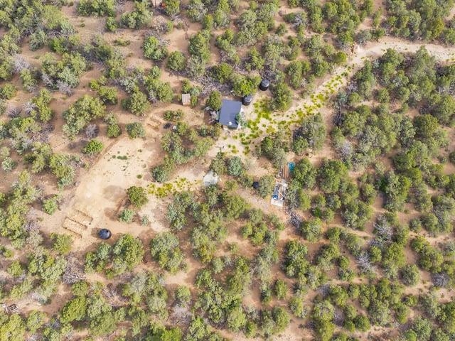 Aerial view of a dry, brush-covered lot with a small roofed structure and cleared areas.