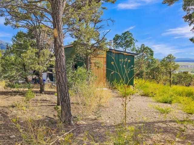 Wooded vacant lot with a small green shed and distant mountain valley.