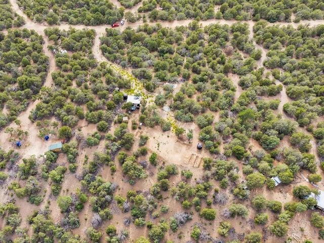 Aerial view of scrub-covered land crossed by dirt tracks, with a road along the upper edge.
