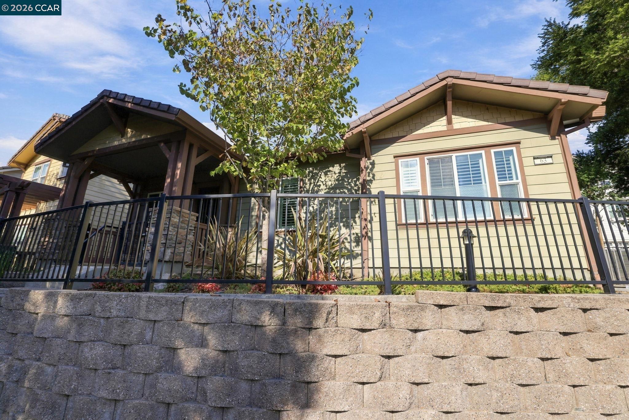 Home exterior with a covered entry, black railing, and stone retaining wall.