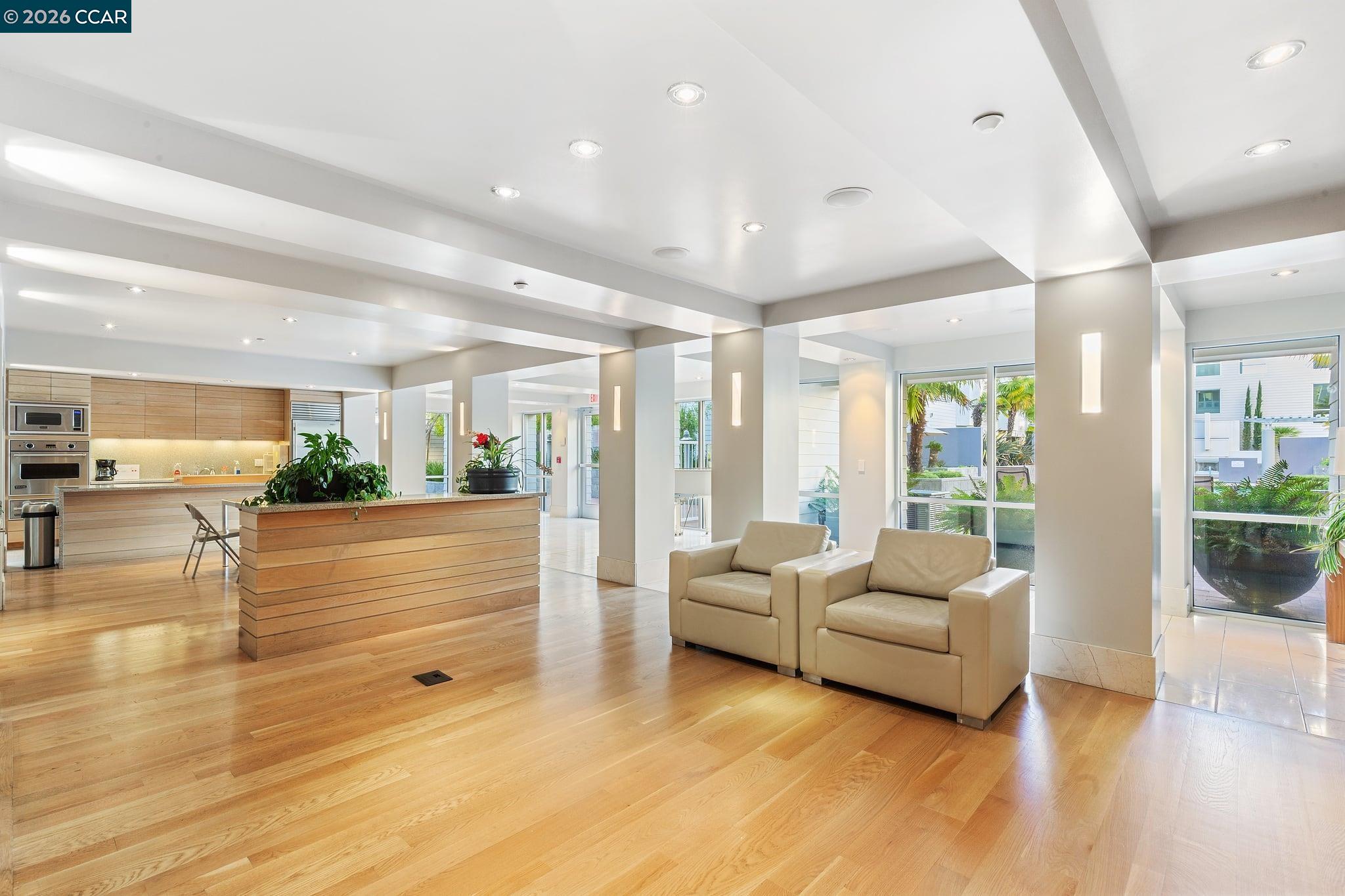 Modern lobby with a wood reception counter, beige armchairs, and large windows.