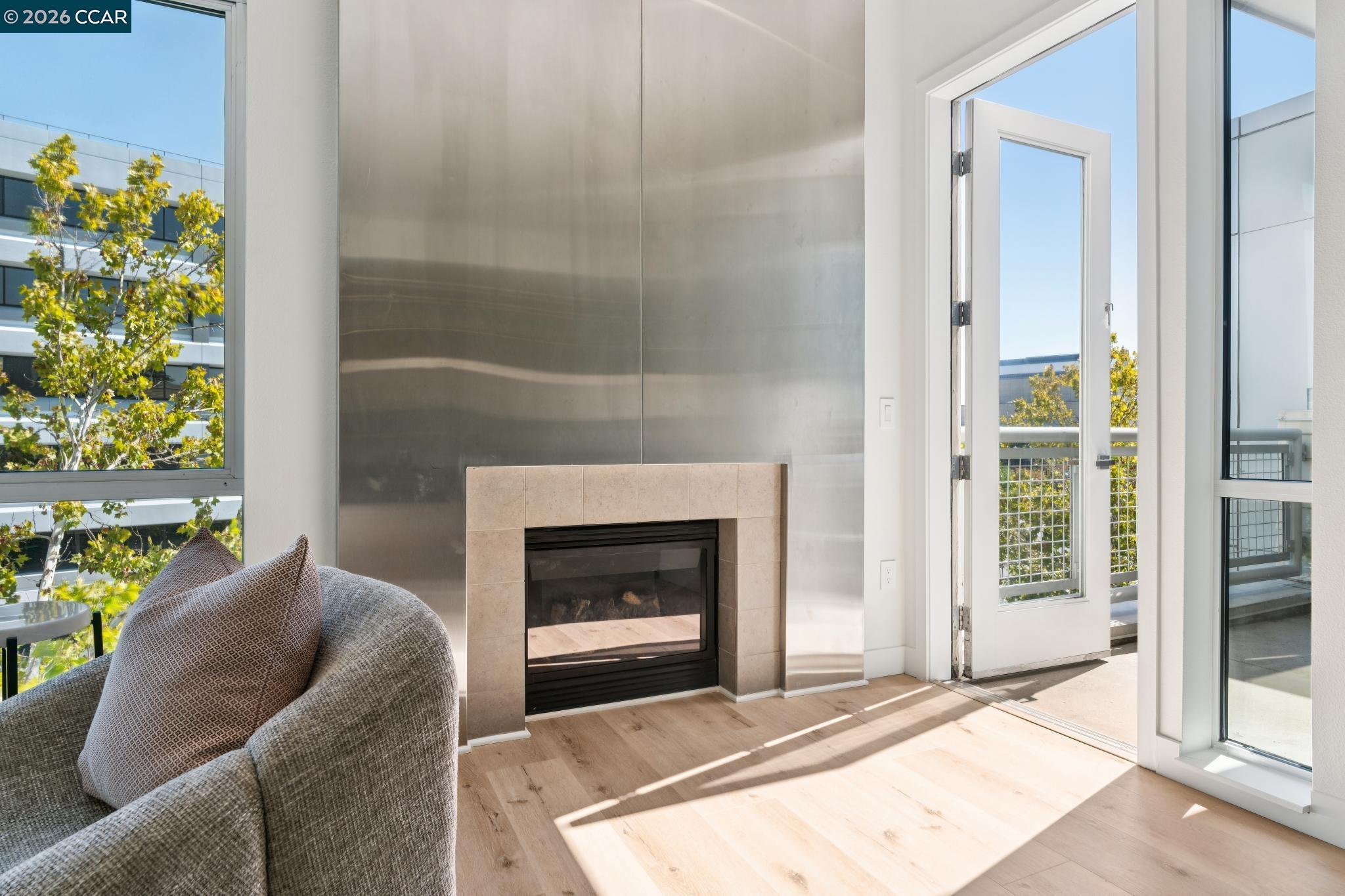 Living room with a tall metal fireplace, gray chair, and open balcony door.