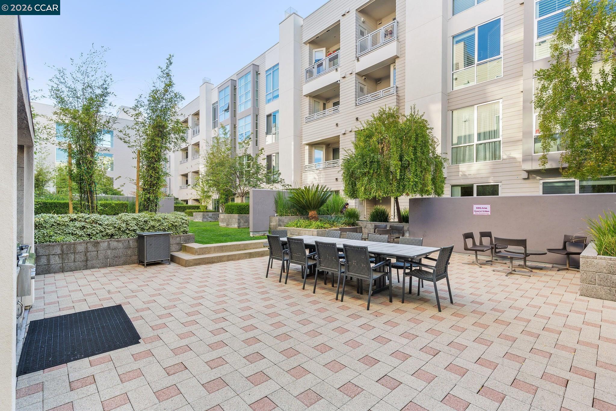 Apartment courtyard patio with communal dining table, lounge chairs, and landscaped planters.