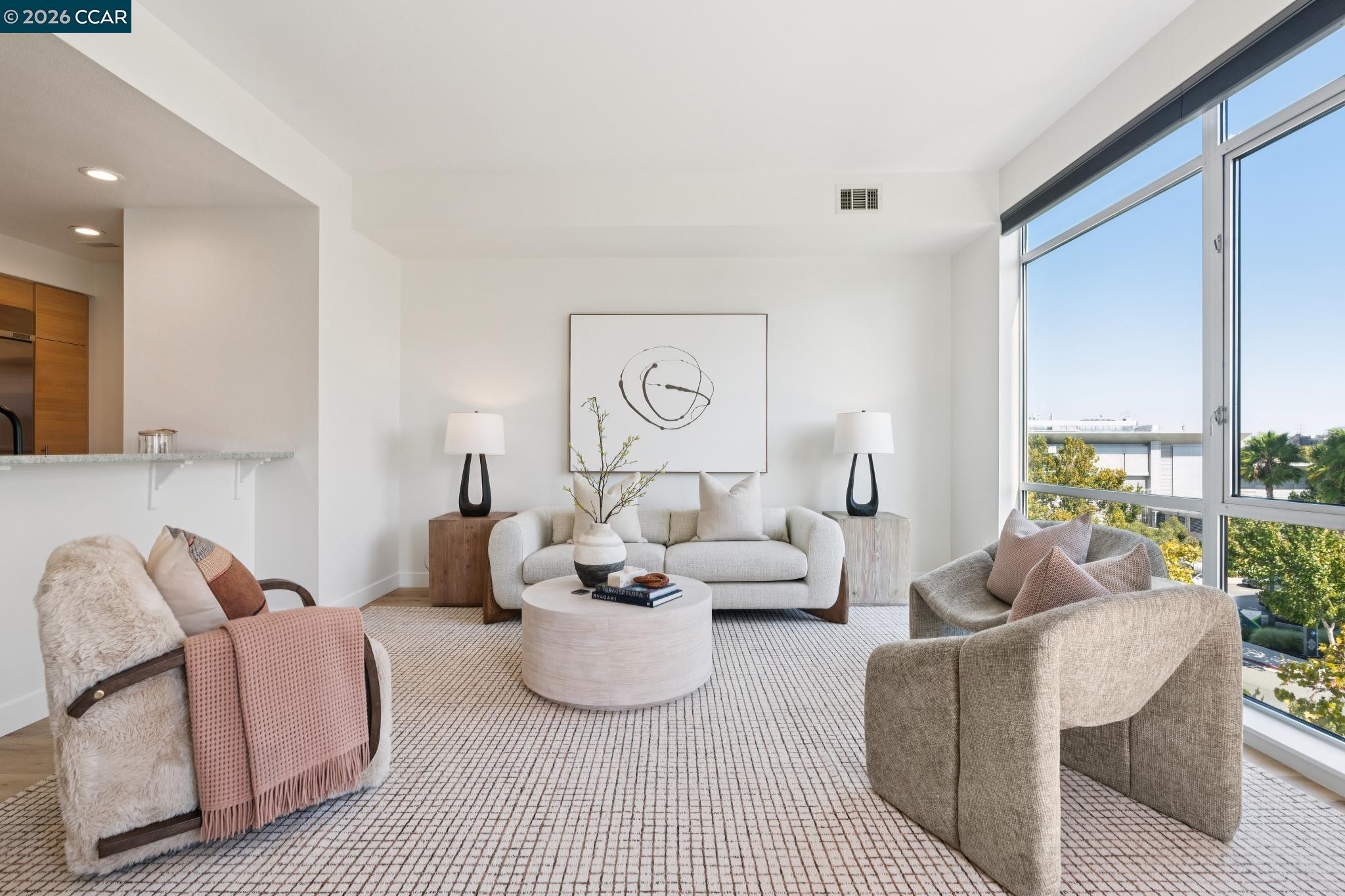 Staged condo living room with floor-to-ceiling windows, a white sofa, and an open kitchen.