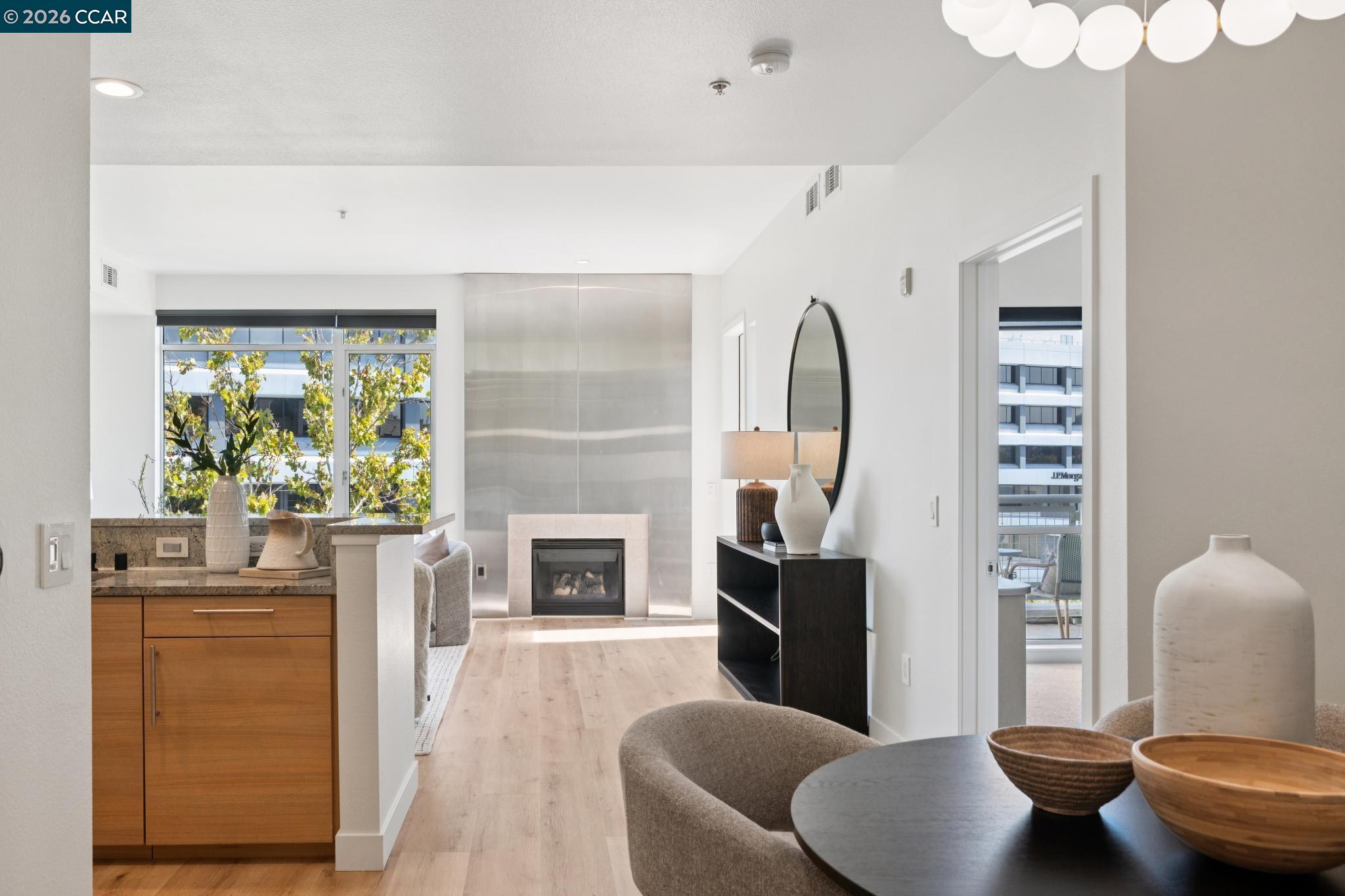 Open-plan condo living area with a fireplace, kitchen peninsula, and large windows.
