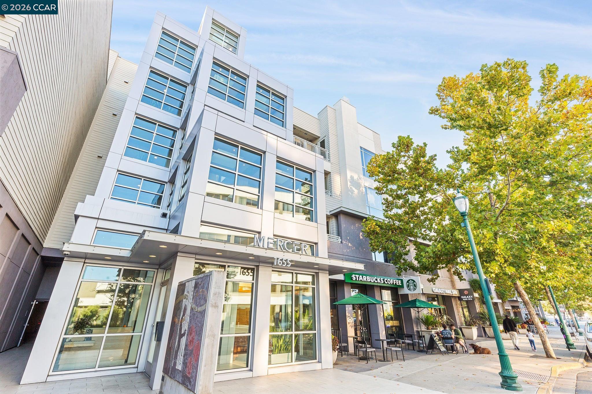 Mercer building exterior with large windows, street-level shops, and yellow-leaved trees.