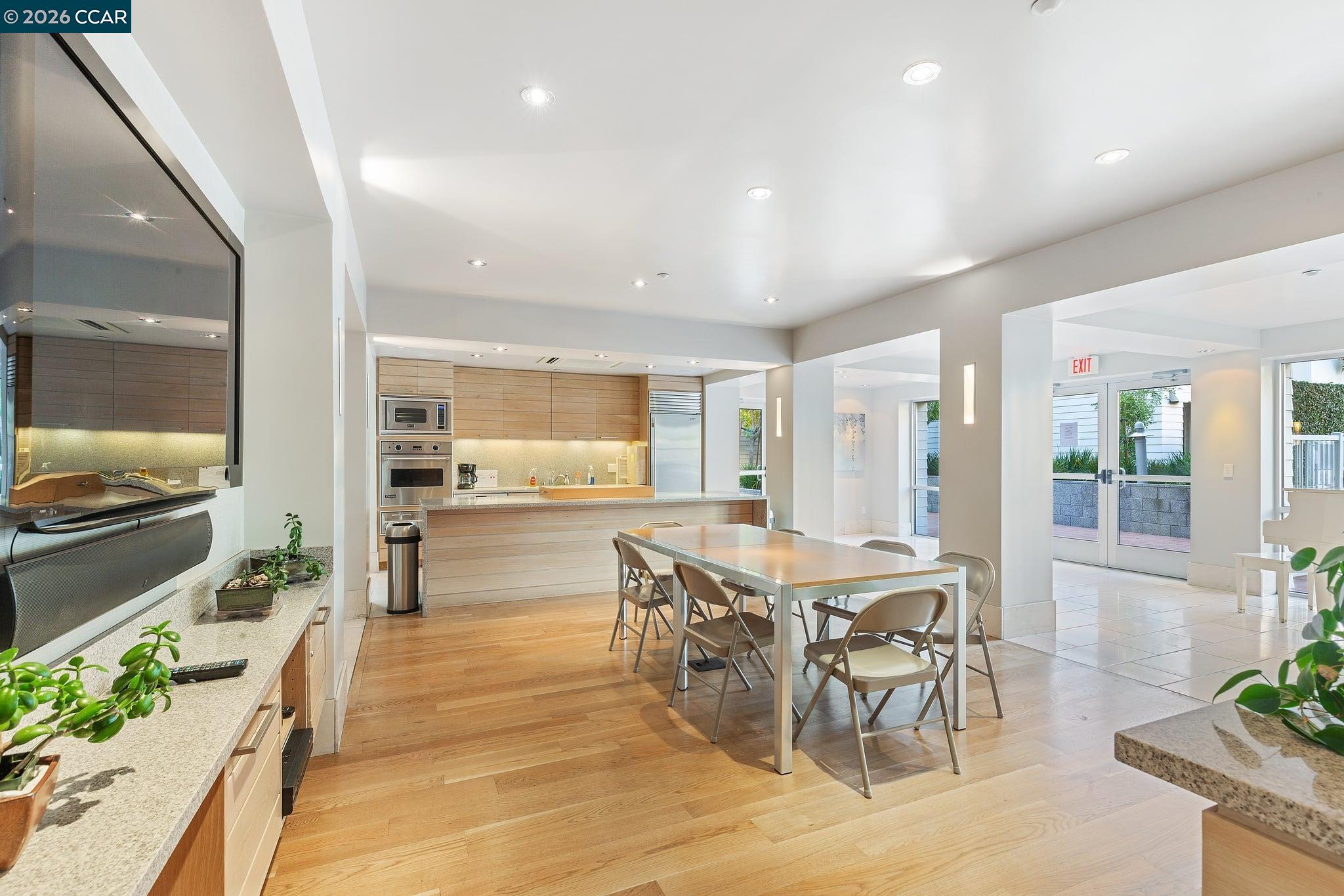Open kitchen and dining area with light wood cabinetry, stainless steel appliances, and glass patio doors.