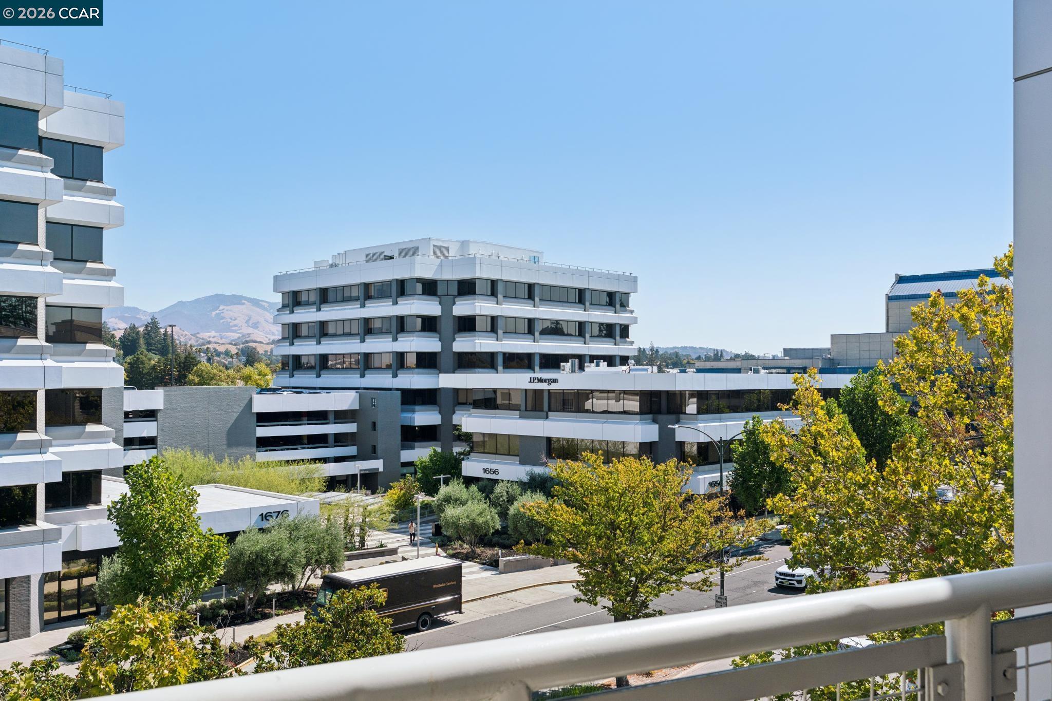 Modern office buildings and tree-lined streets, with distant hills beyond.