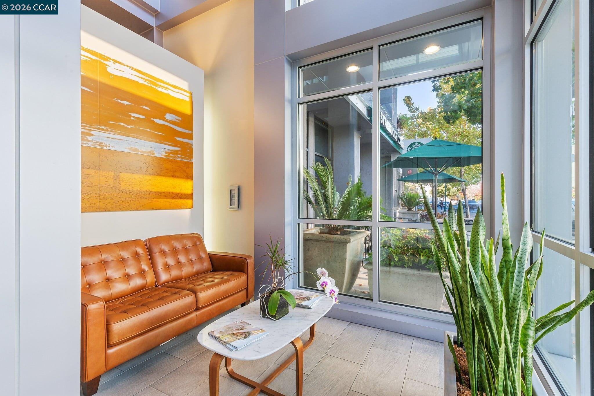 Lobby seating area with a cognac leather sofa and floor-to-ceiling windows overlooking a landscaped patio.