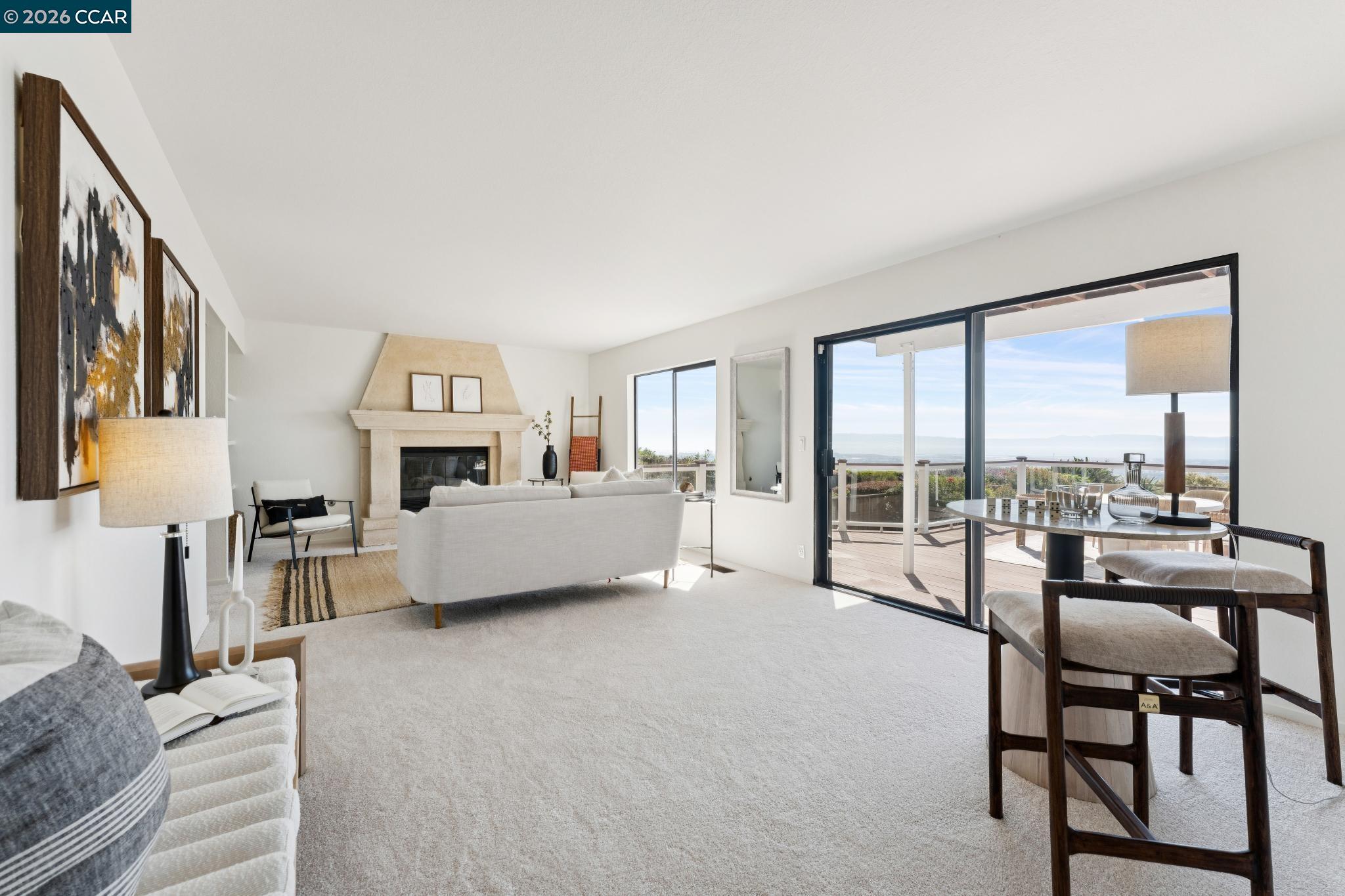Furnished living room with a stone fireplace and sliding doors onto a deck overlooking the water.