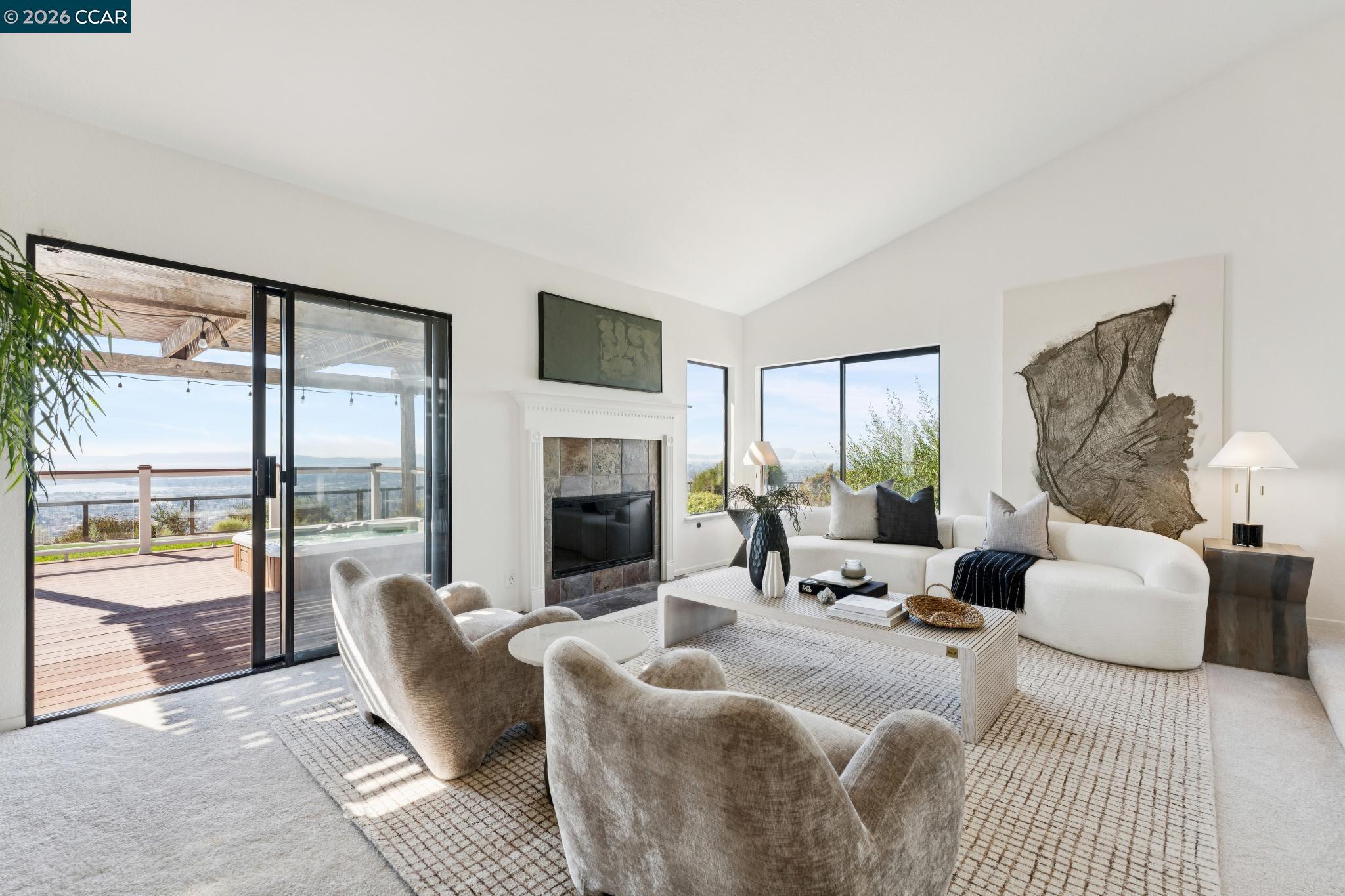Bright living room with fireplace, curved seating, and sliding doors to a deck overlooking water.