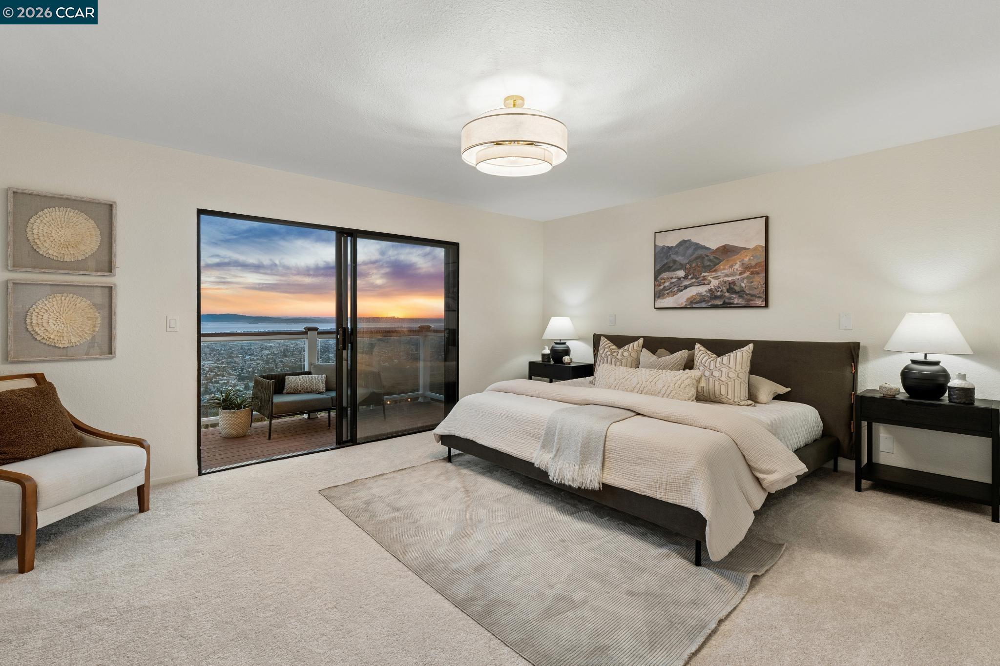 Staged bedroom with a king bed and sliding doors overlooking the ocean at sunset.