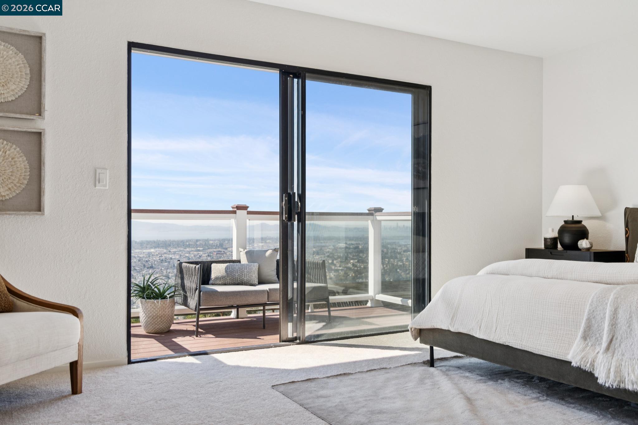 Bedroom opening onto a balcony with seating and an elevated view over Oakland.
