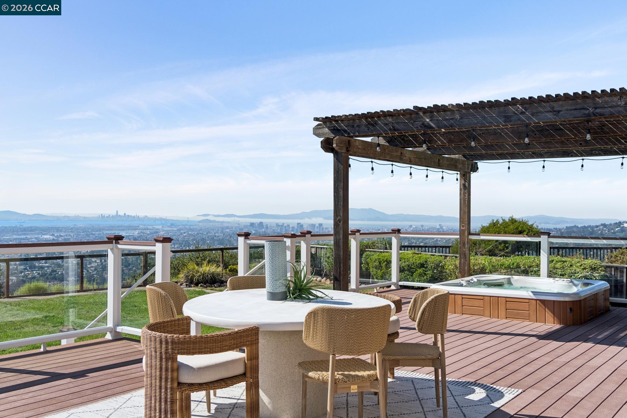 Deck with pergola, hot tub, and dining area overlooking the Bay Area skyline.