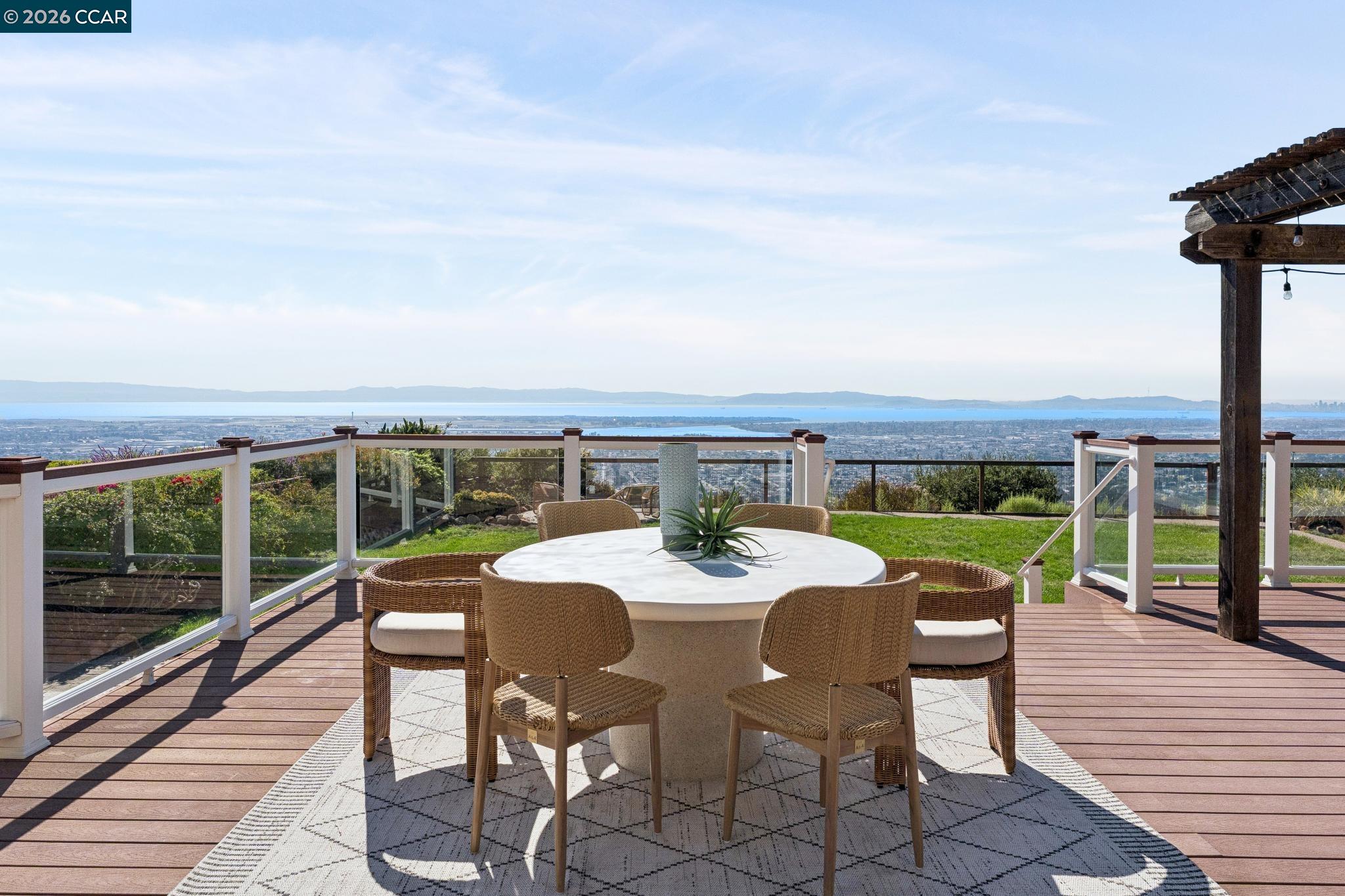 Outdoor deck dining area with wicker chairs and expansive city and bay views.