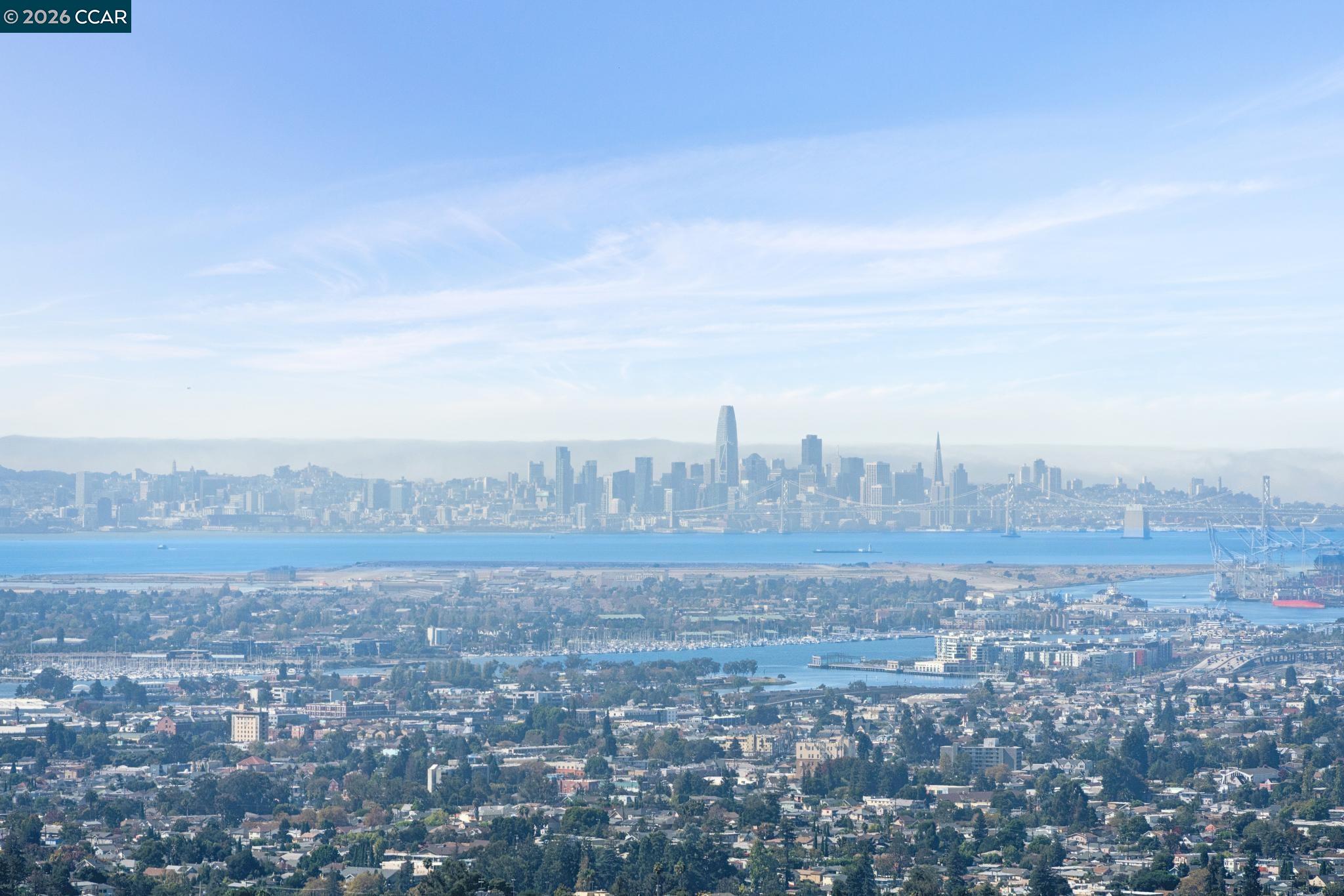Panoramic view of San Francisco across the bay, with the skyline and Bay Bridge beyond Oakland neighborhoods.