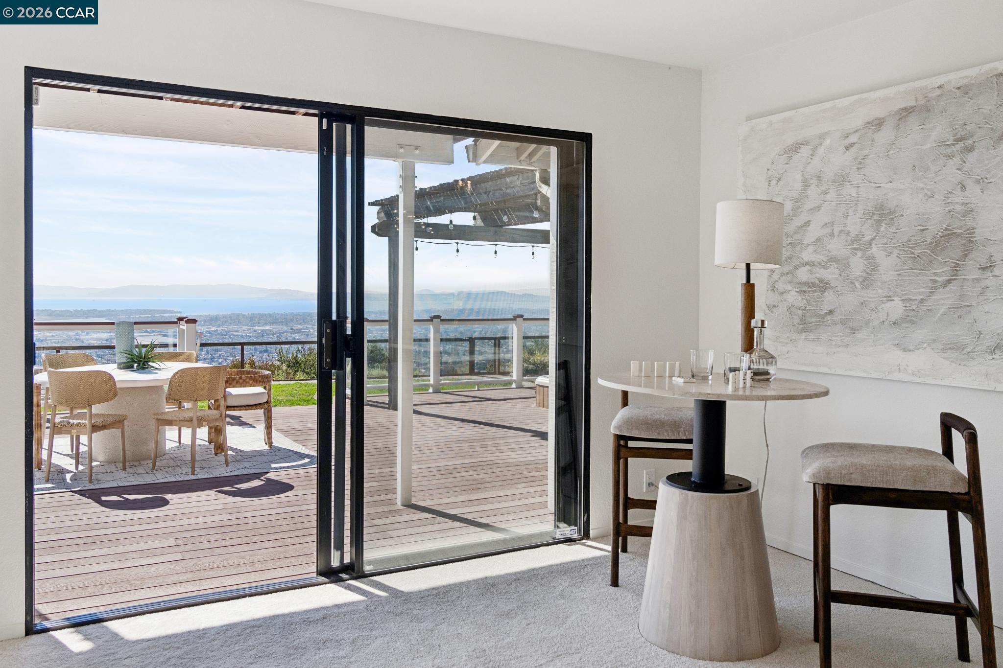 Sitting area opening onto a deck, with a broad water view beyond.