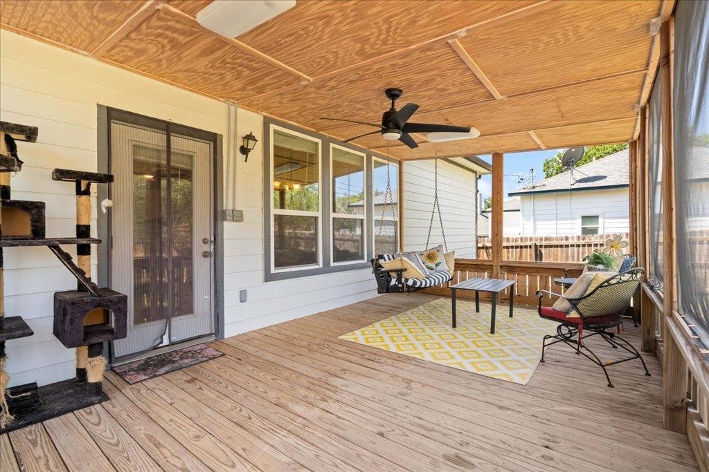 Covered porch with a wood-plank ceiling, porch swing, and seating around a coffee table.