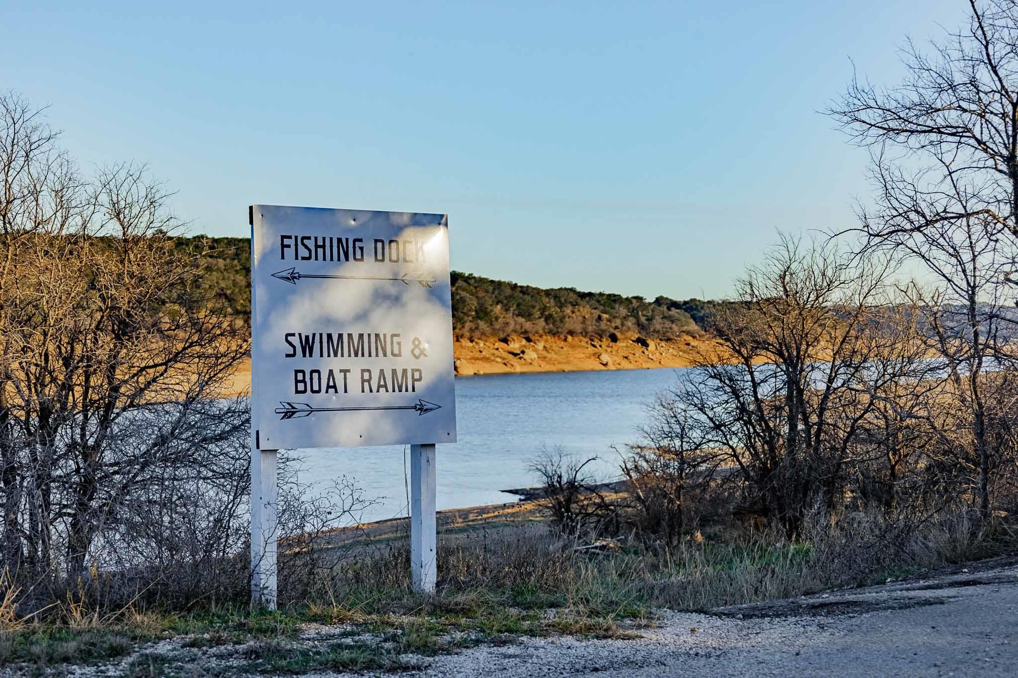 Lakeshore sign points toward the fishing dock and swimming and boat ramp.