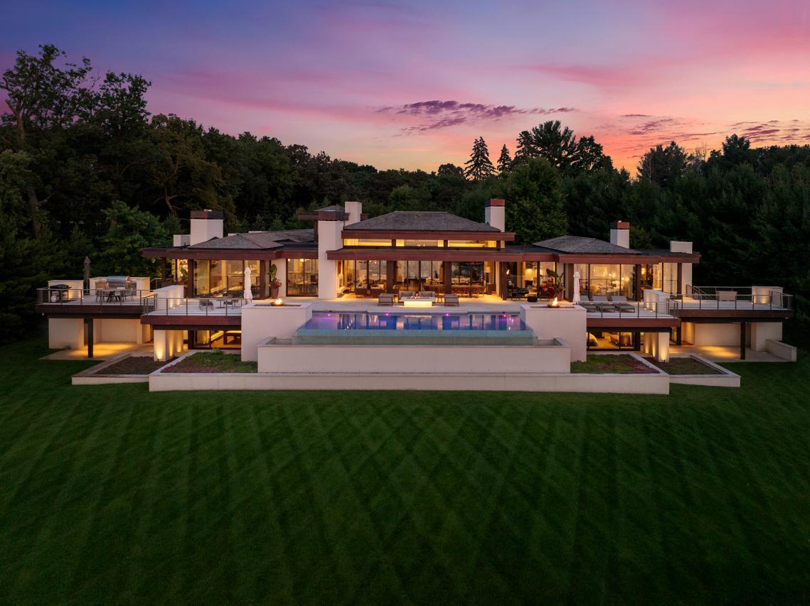 Modern luxury home with a central pool and wide terraces at sunset