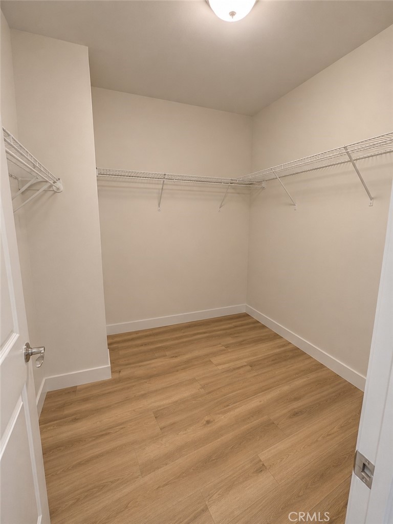 Empty walk-in closet with wood-look flooring and wire shelving on three walls.