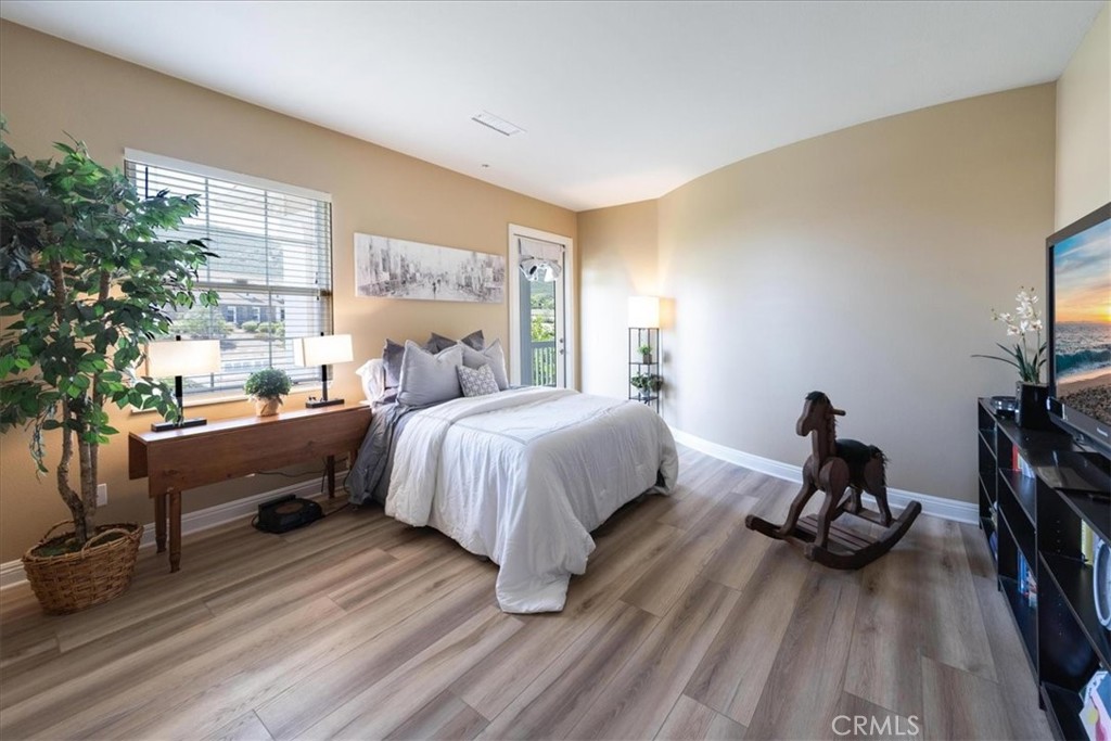 Furnished bedroom with a white bed, wood-look flooring, and a wooden rocking horse.
