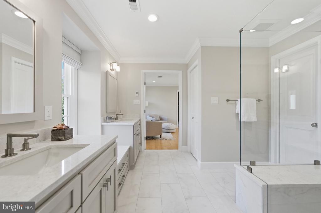 Bathroom with a long white vanity, marble-look counters, and a glass-enclosed shower.