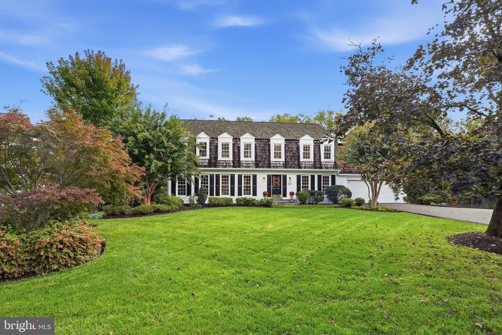 Two-story house with dormer windows, an attached garage, and a broad green lawn.