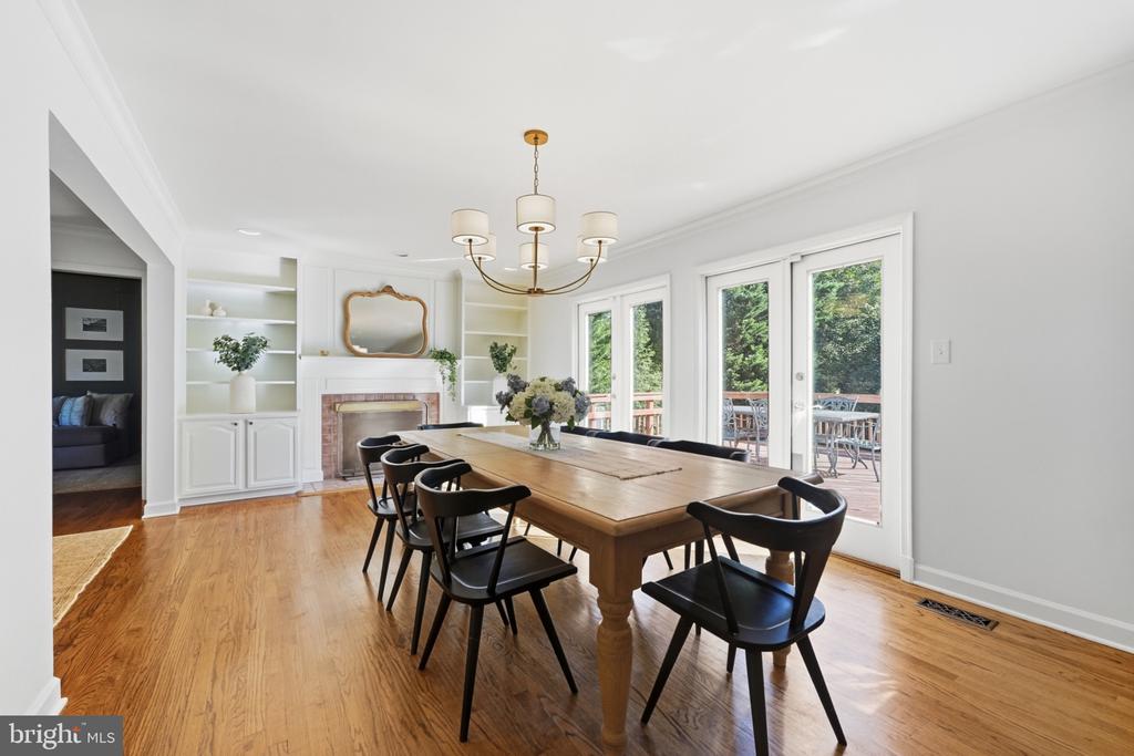 Dining room with built-in fireplace cabinetry, a long wooden table, and glass doors to a deck.