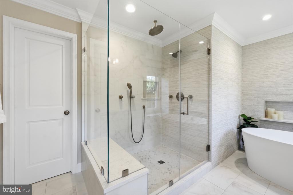 Modern bathroom with a glass-enclosed marble shower, built-in bench, and freestanding soaking tub.