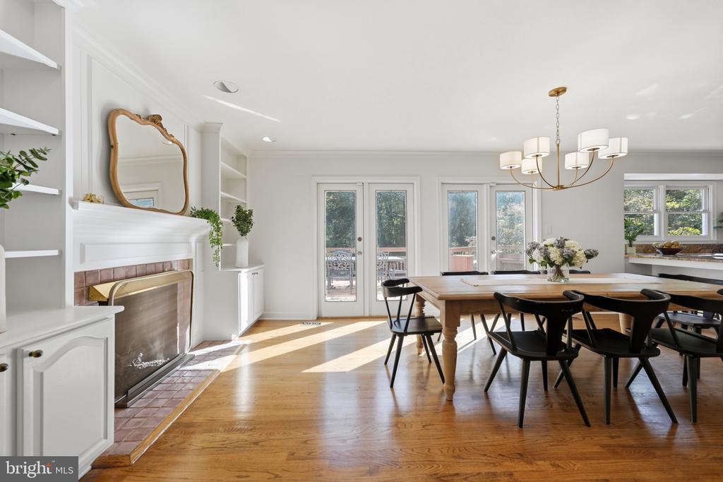 Dining room with a long wooden table, black chairs, and a brick fireplace.
