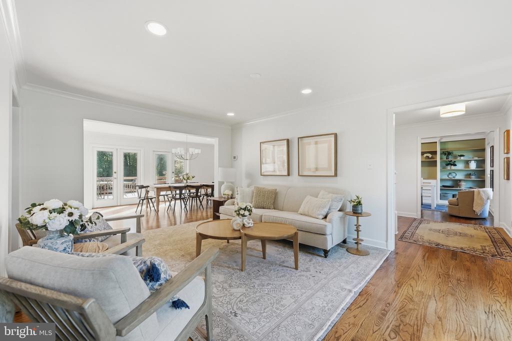 Staged living room with neutral sofas, a patterned rug, and an adjoining dining area.