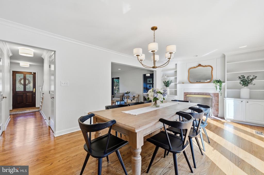 Dining room with a large wood table, black chairs, built-in shelving, and a fireplace.
