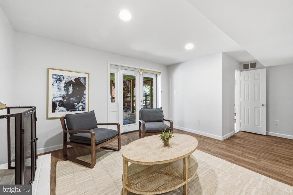 Furnished sitting area with two gray chairs, an oval coffee table, and glass doors.