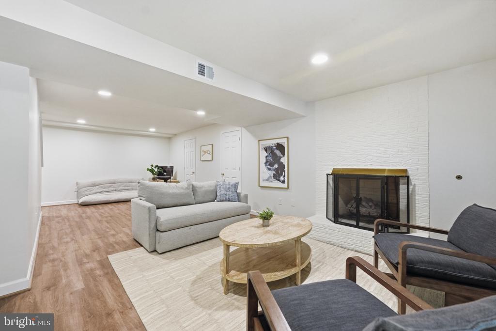 Furnished living room with a white fireplace, gray sofas, and wood-look flooring.