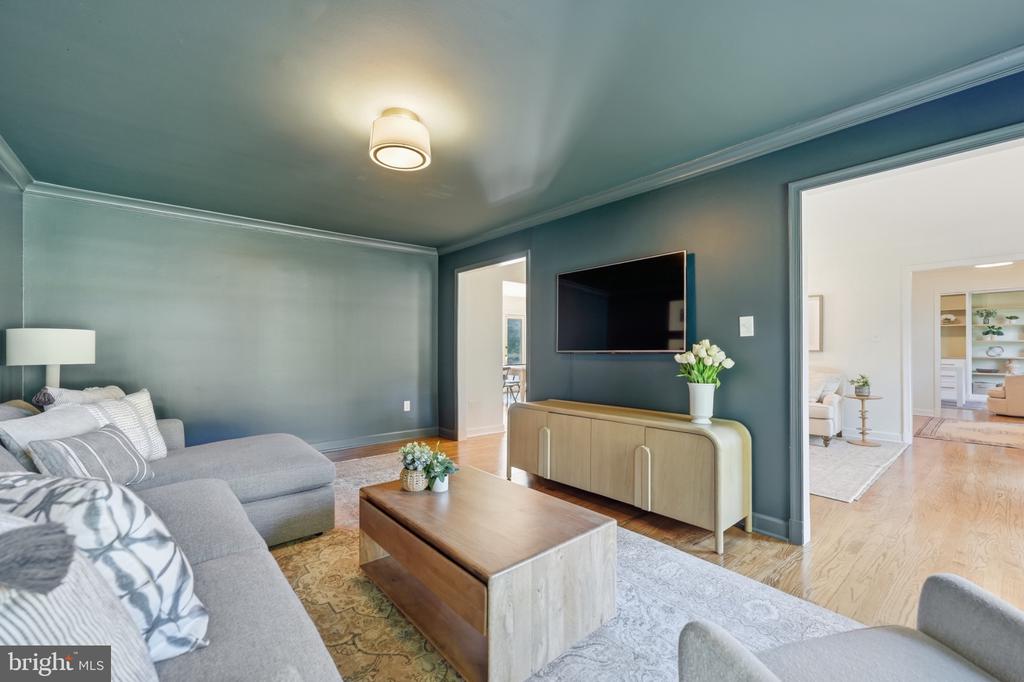 Living room with a gray sectional, wood coffee table, and television against a blue-green wall.