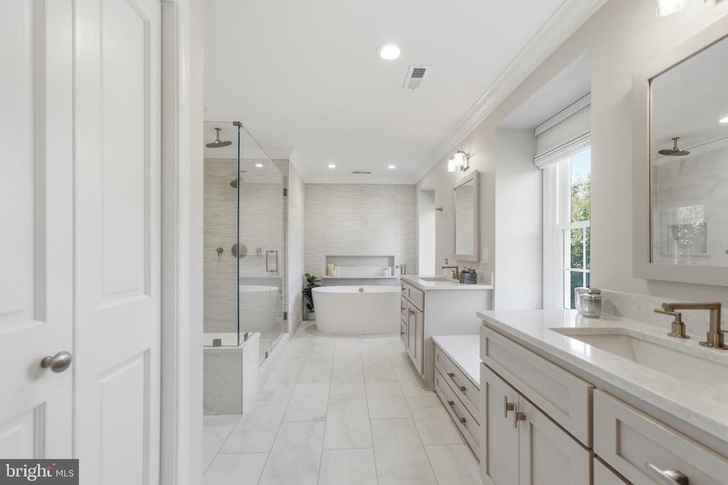 Primary bathroom with a freestanding tub, glass shower, and long double vanity.