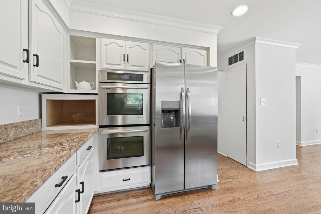 Kitchen with white cabinets, granite counters, stainless appliances, and hardwood floors.