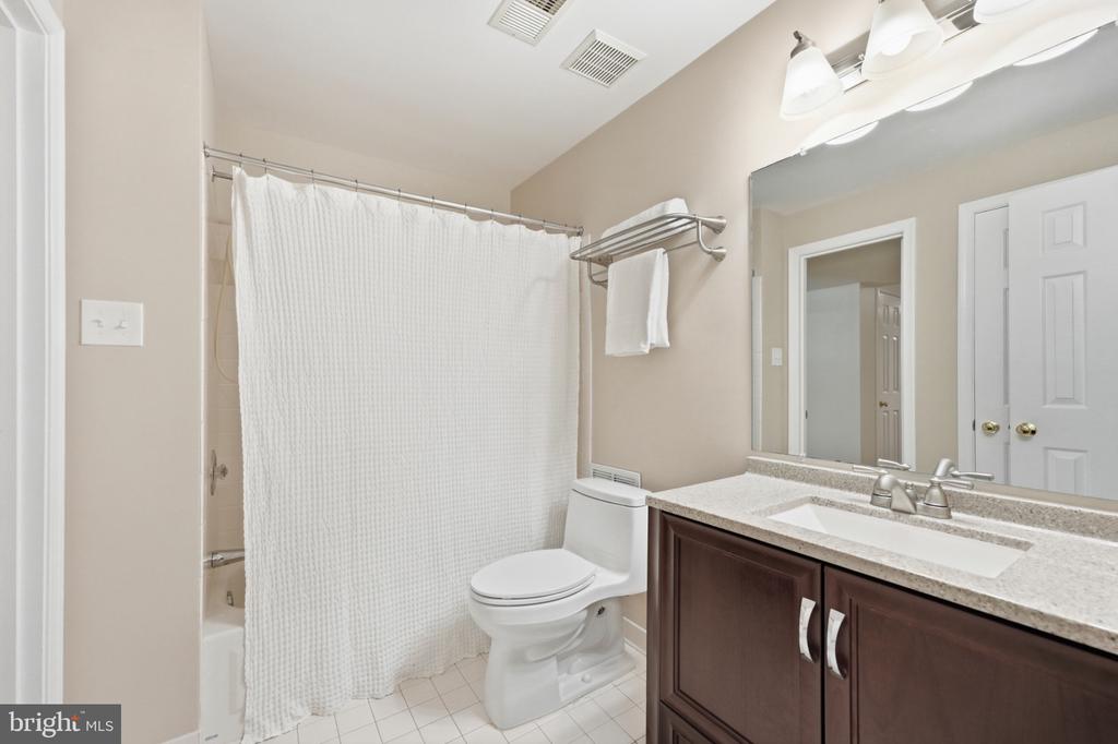 Bathroom with a white shower curtain, toilet, and dark wood vanity.