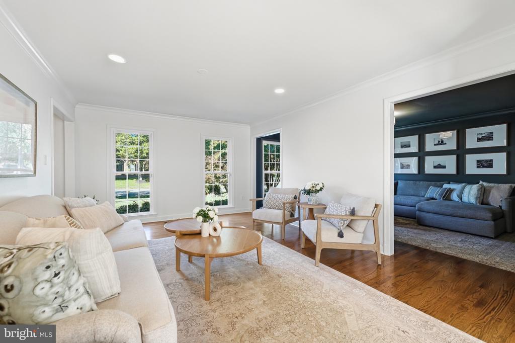 Living room with white seating, hardwood floors, tall windows, and an adjoining blue sitting room.