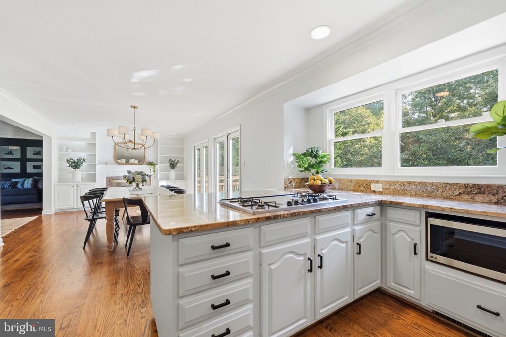 Bright kitchen with white cabinets, granite counters, gas cooktop, and a dining area with built-in shelving.