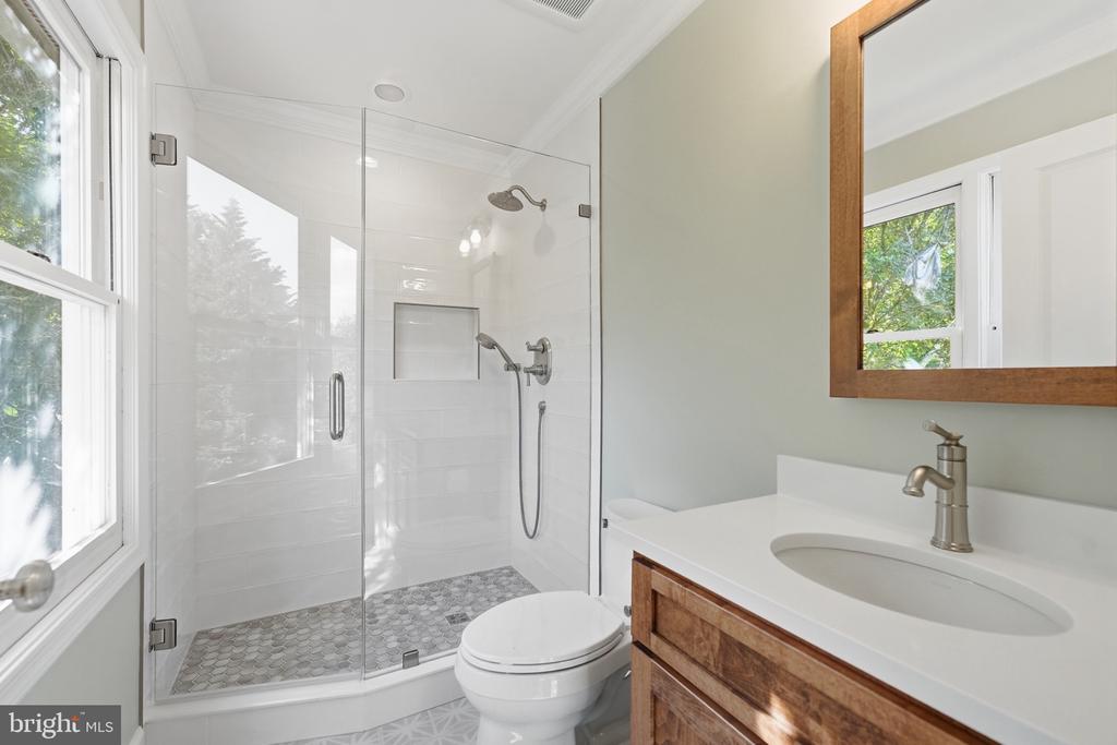 Bathroom with a glass walk-in shower, wood vanity, and large window.