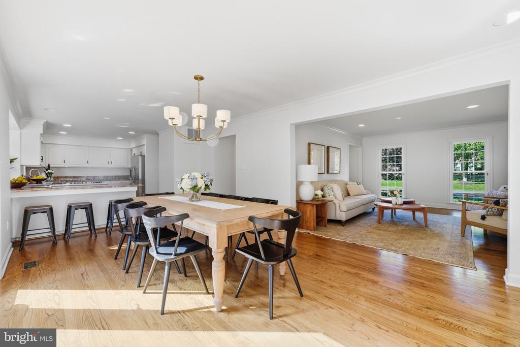 Open-plan kitchen, dining area, and living room with white cabinetry and a wood dining table.