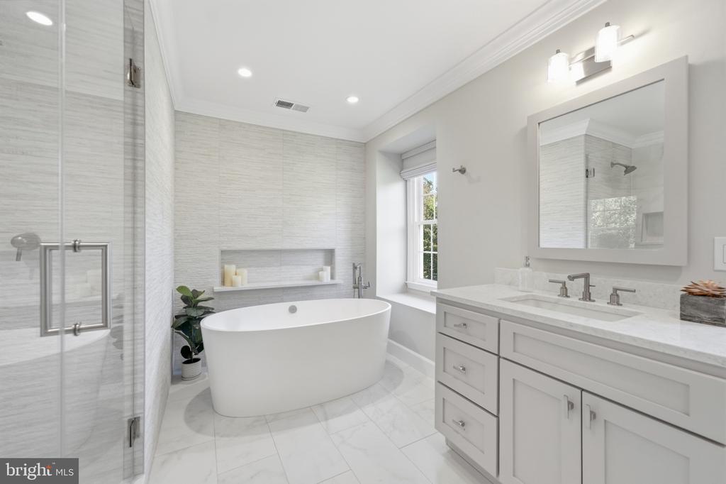 Bright bathroom with a freestanding soaking tub, glass shower, and white double vanity.