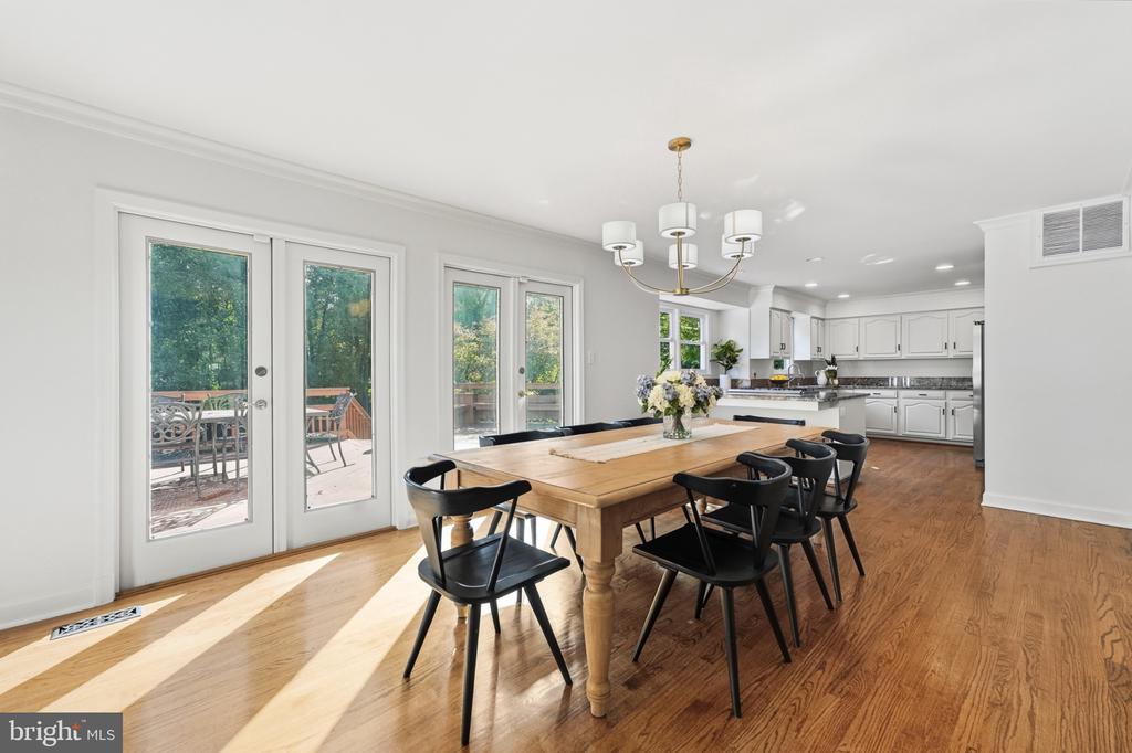Dining room with a wooden table and black chairs beside glass doors opening to a deck.
